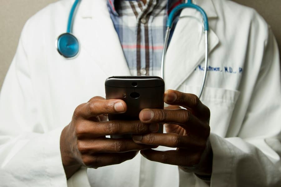A healthcare professional uses a phone while providing patient care.